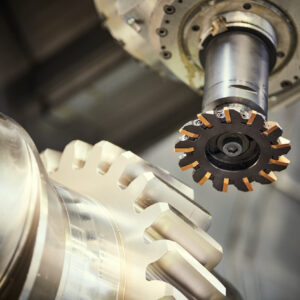 milling metalworking process. Industrial CNC machining of tooth gear on shaft by vertical mill cutting at factory